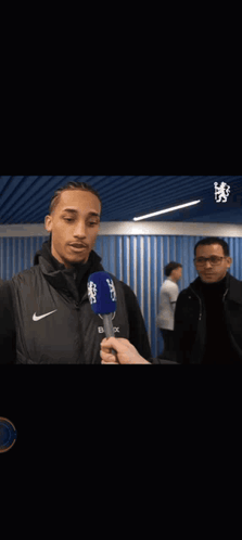 A Man Is Hugging Another Man While Holding A Microphone That Says Cbs On It GIF