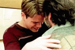 A Man Is Hugging Another Man Who Is Crying And Holding His Shoulder . GIF