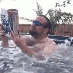 A Man Is In A Hot Tub Reading A Magazine GIF