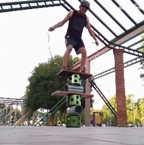 A Man Is Jumping A Rope While Standing On A Stack Of Barrels With The Letter B On Them GIF