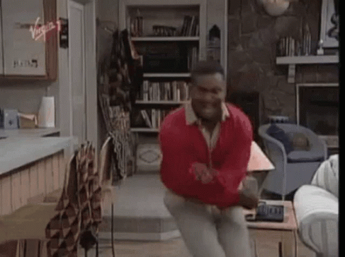A Man Is Jumping In The Air In A Living Room . GIF