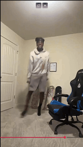 A Man Is Jumping In The Air In A Room With A Chair And Skateboards GIF