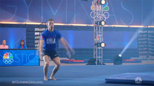 A Man Is Jumping In The Air In Front Of A Sign That Says ' Olympic Dreams ' GIF