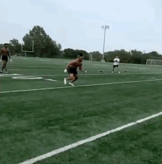 A Man Is Jumping In The Air On A Football Field GIF