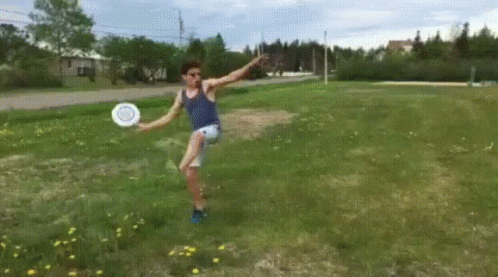 A Man Is Jumping In The Air While Holding A Frisbee In A Field GIF