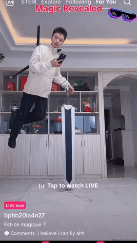 A Man Is Jumping In The Air While Holding A Sword And Looking At His Cell Phone GIF
