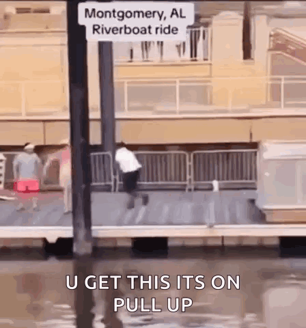 A Man Is Jumping Into A Body Of Water Next To A Sign That Says Montgomery Al Riverboat Ride GIF