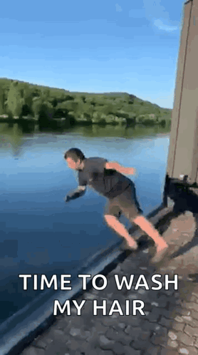 A Man Is Jumping Into A Body Of Water With The Words `` Time To Wash My Hair '' . GIF