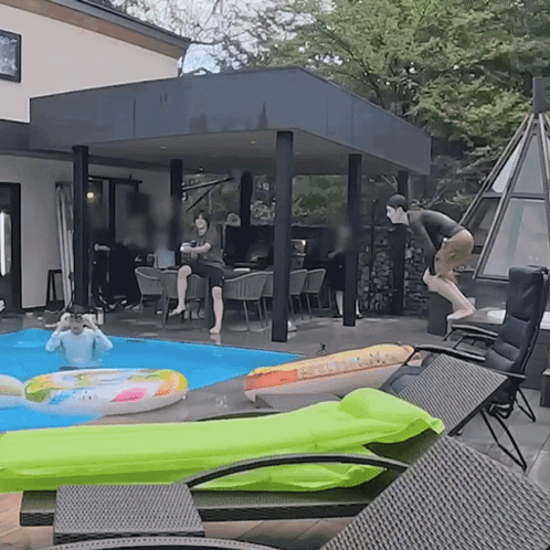 A Man Is Jumping Into A Pool With A Green Float GIF