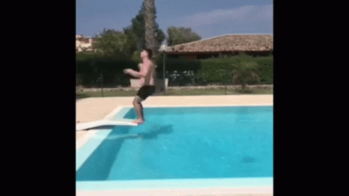A Man Is Jumping Into A Swimming Pool . GIF