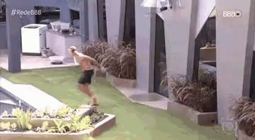 A Man Is Jumping Into A Swimming Pool While Wearing Shorts . GIF