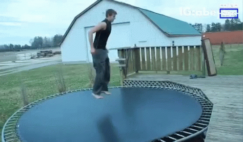 A Man Is Jumping On A Trampoline In Front Of A Barn And A Sign That Says Globe News GIF