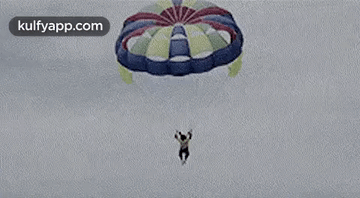 A Man Is Jumping Out Of A Parachute Into The Air . GIF