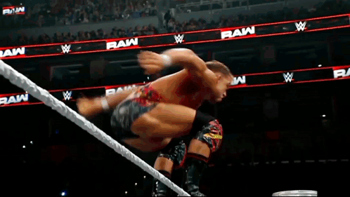 A Man Is Jumping Over A Rope In A Wrestling Ring With The Word Raw In The Background GIF