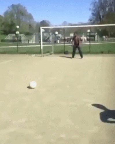A Man Is Kicking A Soccer Ball In A Field GIF