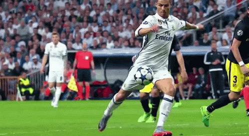 A Man Is Kicking A Soccer Ball On A Field . GIF