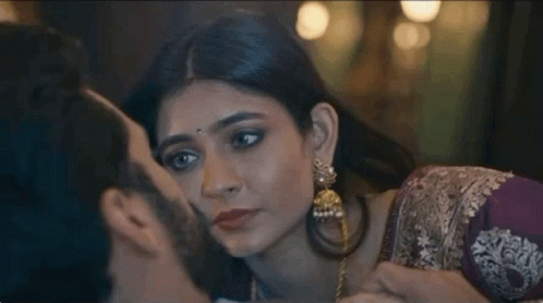 A Man Is Kissing A Woman On The Cheek In A Close Up . GIF