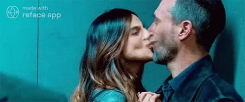 A Man Is Kissing A Woman On The Cheek . GIF