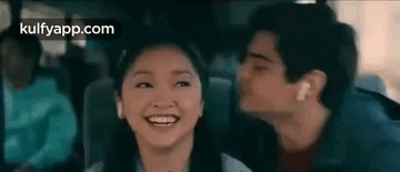 A Man Is Kissing A Woman On The Cheek While They Are Sitting In A Car . GIF