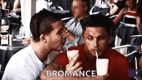A Man Is Kissing Another Man On The Cheek While Holding A Drink . GIF