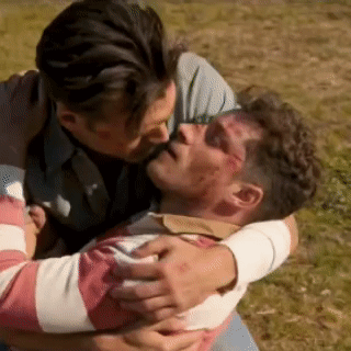 a man is kissing another man on the forehead while they are hugging each other .
