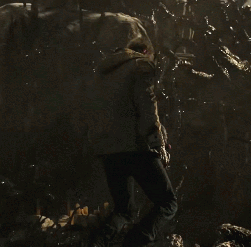 A Man Is Kneeling Down In A Dark Room GIF