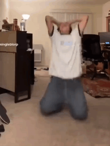 a man is kneeling down in a living room with his arms outstretched