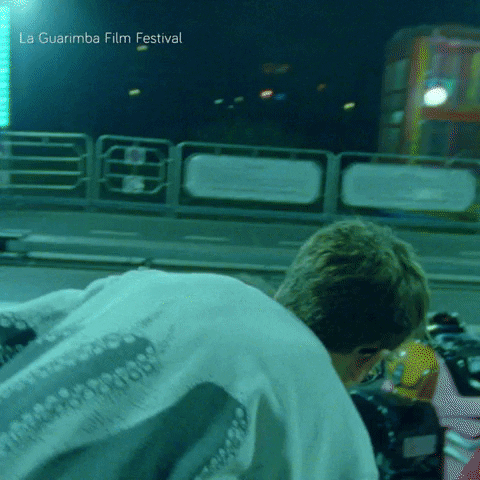 A Man Is Kneeling Down In Front Of A La Guarimba Film Festival Sign GIF