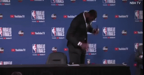 a man is kneeling down in front of a wall that says nba finals on it