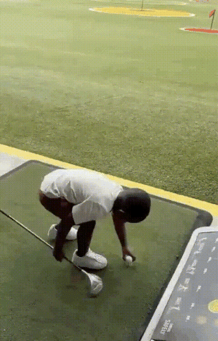 A Man Is Kneeling Down On A Golf Course With A Golf Club In His Hand GIF