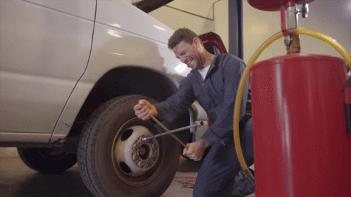 A Man Is Kneeling Down To Change A Tire GIF