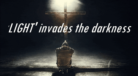 A Man Is Kneeling In Front Of A Cross With The Words Light Invades The Darkness Above Him GIF