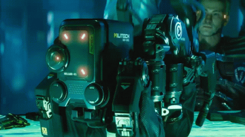 A Man Is Kneeling Next To A Robot That Has The Number 10 On It GIF