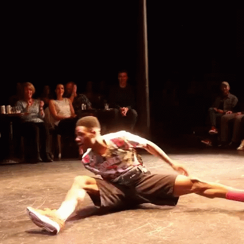 A Man Is Kneeling On The Floor In Front Of A Crowd GIF