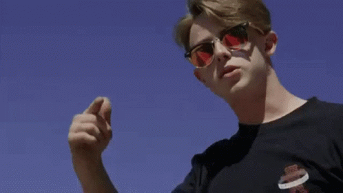 A Man Is Kneeling On The Ground In Front Of A Large Building . GIF
