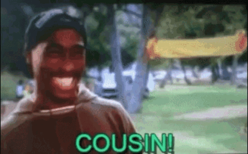 A Man Is Laughing In A Park With The Word Cousin Written On The Screen . GIF