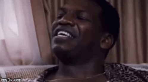 A Man Is Laughing With His Eyes Closed And His Mouth Open . GIF