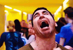 A Man Is Laughing With His Mouth Wide Open In A Crowded Room . GIF