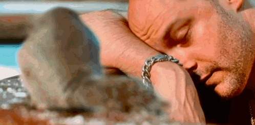 A Man Is Laying Down With His Head On His Wrist . GIF