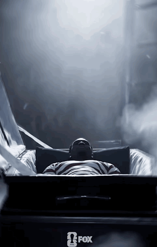 A Man Is Laying In A Coffin With A Fox Logo On The Bottom GIF