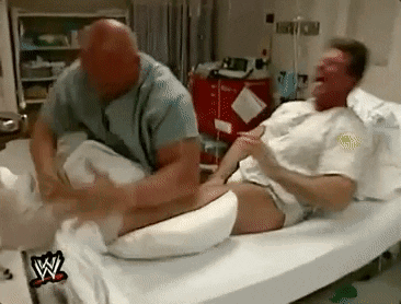 a man is laying in a hospital bed getting a massage from a nurse .