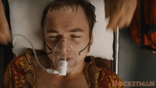 A Man Is Laying In A Hospital Bed With An Oxygen Mask On His Face .. GIF