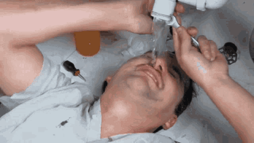A Man Is Laying In A Sink With His Eyes Closed GIF
