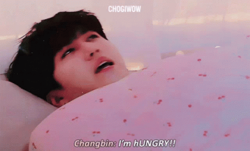 A Man Is Laying In Bed With His Mouth Open And Says Changbin I 'M Hungry ! GIF