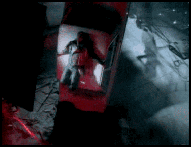 A Man Is Laying In The Back Of A Red Car In A Dark Room GIF