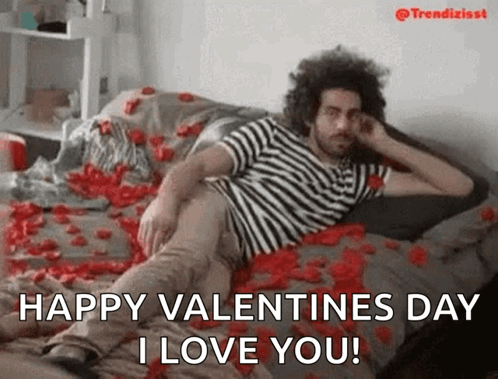 A Man Is Laying On A Bed Covered In Rose Petals And Says Happy Valentines Day I Love You . GIF