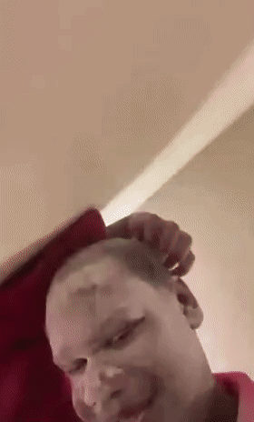 A Man Is Laying On A Bed With A Red Pillow On His Head . GIF