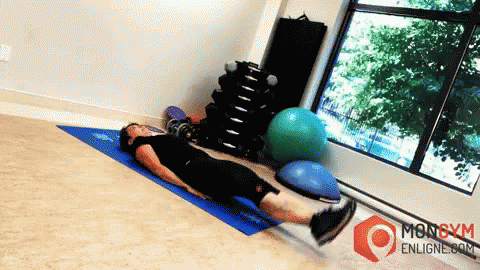 A Man Is Laying On A Blue Mat In A Gym With A Mongym Enligne.com Logo GIF