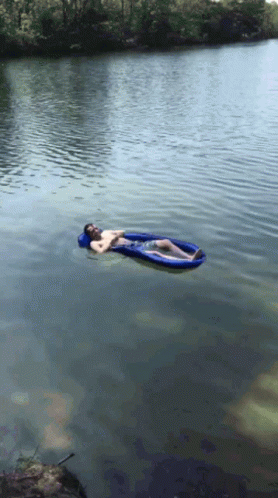 a man is laying on a blue raft in the water