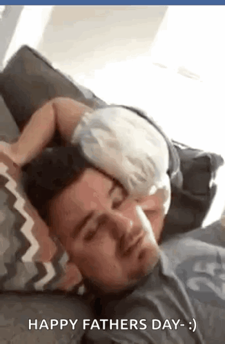 A Man Is Laying On A Couch With A Baby On His Shoulder . GIF